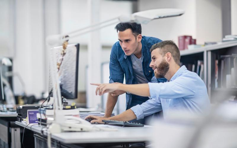 zwei Männer besprechen etwas am Bildschirm